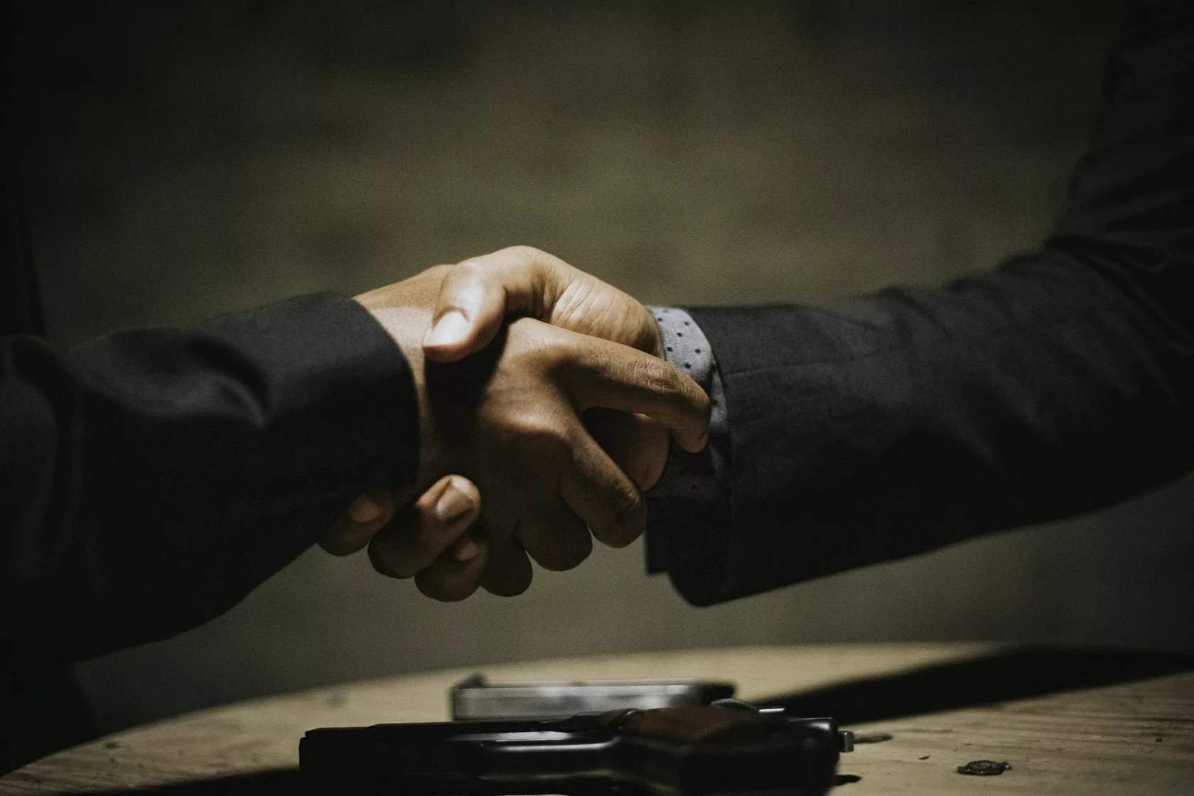 Dos profesionales se estrechan la mano sobre una mesa de madera tras cerrar un acuerdo